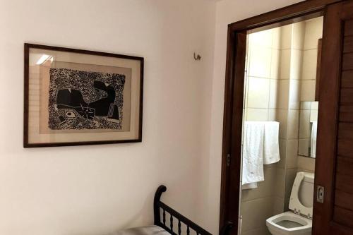 ein Bad mit einem WC und einem Bild an der Wand in der Unterkunft Casa em condomínio fechado na Serra Guaramiranga in Pernambuquinho
