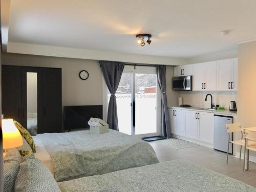 a bedroom with two beds and a kitchen with a window at Grandravine/Beautiful Unit near downtown Toronto in Toronto