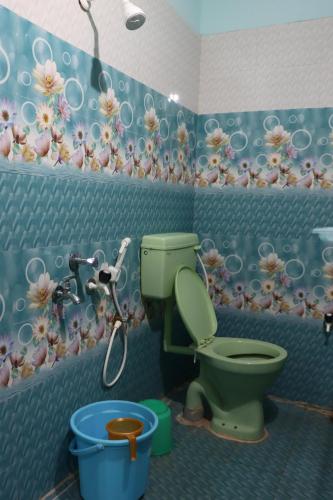a bathroom with a green toilet and flowers on the wall at G.M Luxury Hotel in Srīsailam