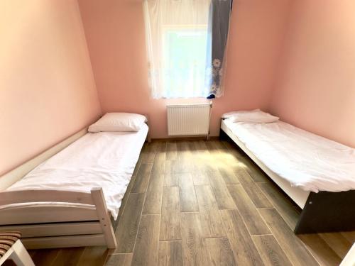 two beds in a small room with a window at Apartament 4 osobowy obok Szpitala Brzeziny 2 pokoje Prywatna łazienka i kuchnia 32m2 in Brzeziny
