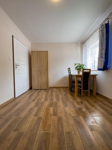 sala de estar con suelo de madera y mesa en Apartament 4 osobowy obok Szpitala Brzeziny 2 pokoje Prywatna łazienka i kuchnia 32m2 en Brzeziny