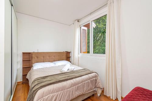 1 dormitorio con cama y ventana en 2D no Centro de Gramado, à 500m da Rua Coberta, en Gramado