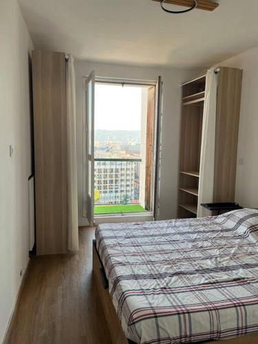 une chambre avec un lit et une grande fenêtre dans l'établissement Charmant type 2 au cœur de la ville, à Marseille