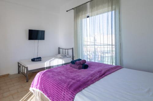 a bedroom with a bed with a purple blanket on it at Delight apartment LA in Larisa