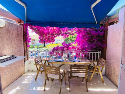 a table on a balcony with purple flowers at Duplex face mer . Cavalière le Lavandou 3 chambres in Le Lavandou