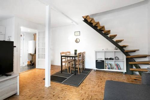 a living room with a table and a staircase at Lejlighed/rækkehus med adgang til pool. in Vipperød