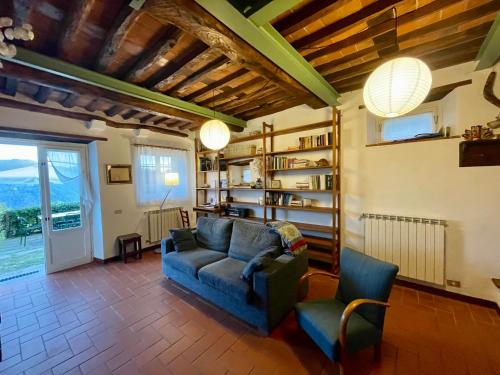 sala de estar con sofá azul y 2 sillas en La casa In Valli 35, en Bagni di Lucca