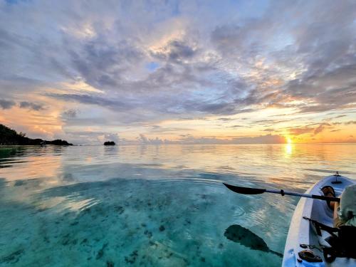 a person paddling a boat in the water at sunset at Moorea Island Beach Hotel in Moorea