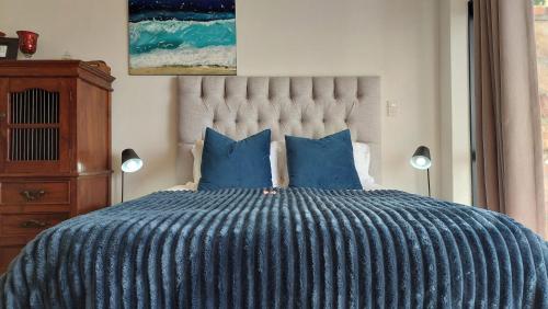 a bed with a blue comforter and two blue pillows at A Relaxing Getaway with Ocean Views in Cape Town