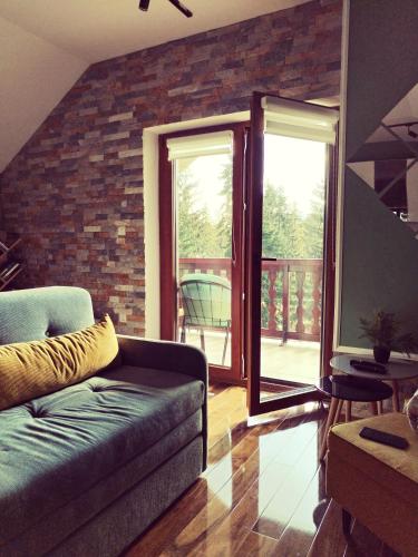 a living room with a couch and a brick wall at Zlatarska Studenica in Brdo
