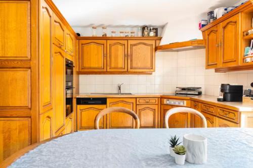 una cocina con armarios de madera y una mesa con sillas. en Chambre d'hôte au milieu des vignes avec magnifique vue sur le lac et jardin, en Féchy