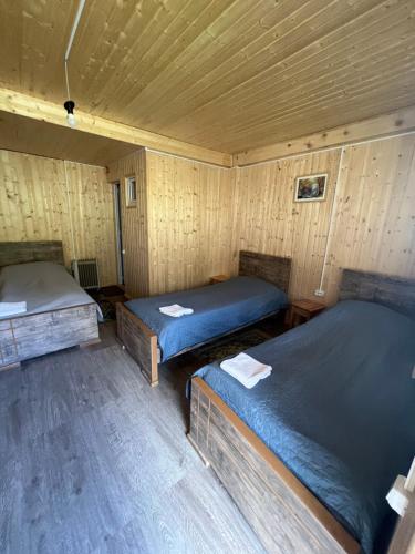 a room with three beds in a wooden cabin at Guesthouse Ivas in Ushguli