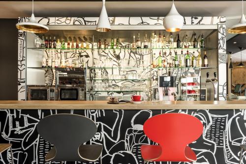 a bar with two chairs in front of a wall covered in graffiti at ibis Bordeaux Centre Bastide in Bordeaux
