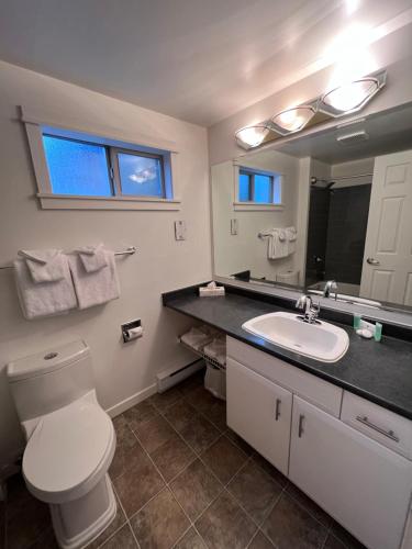 a bathroom with a toilet and a sink and a mirror at Shorewater Resort in Qualicum Beach