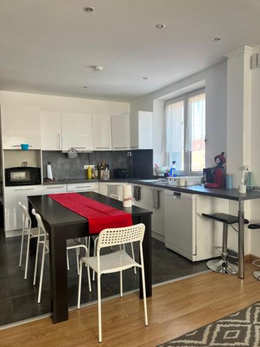 une cuisine avec une table et des chaises noires et une cuisine avec des armoires blanches dans l'établissement casa lola, à Obernai