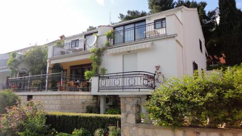 a white house with a balcony and bushes at Guesthouse Apartment Božica in Bol