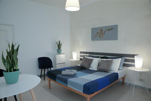 Un dormitorio con una cama azul y una mesa en GUESTHOUSE GRANDI STAZIONI _ bari centro s.l._, en Bari