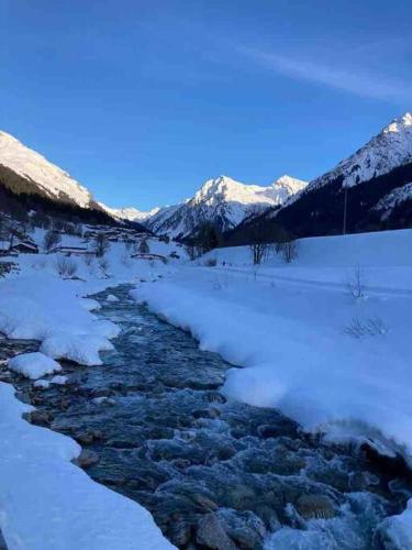 a snow covered river with mountains in the background at Stunning Luxury apartment in Central Klosters in Klosters