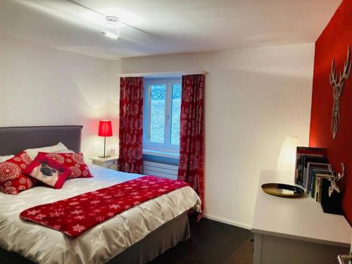 a bedroom with a bed with red curtains and a window at Stunning Luxury apartment in Central Klosters in Klosters
