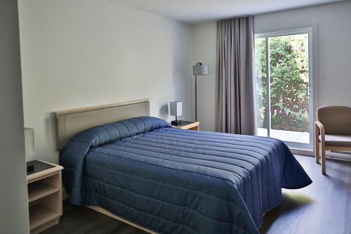um quarto de hotel com uma cama azul e uma janela em Motel Mascouche em Mascouche