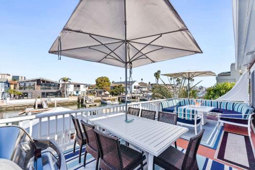 ein Balkon mit Tisch und Stühlen und einem Sonnenschirm in der Unterkunft Stunning BayVIEW Home with Epic Waterfront Views! in Newport Beach