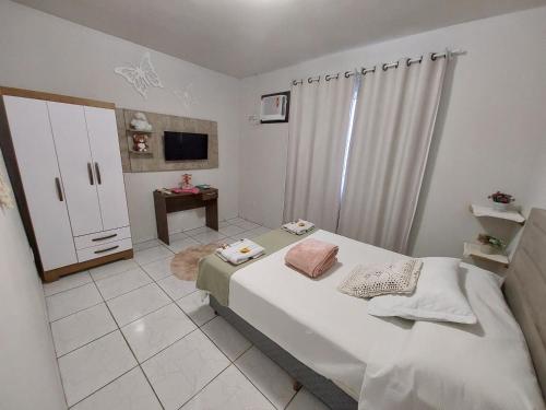 a white bedroom with a bed and a tv at Harmonia Haus in Blumenau