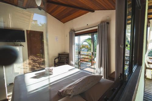 a bedroom with a bed and a large window at POUSADA ENCANTO DO AMOR in Búzios