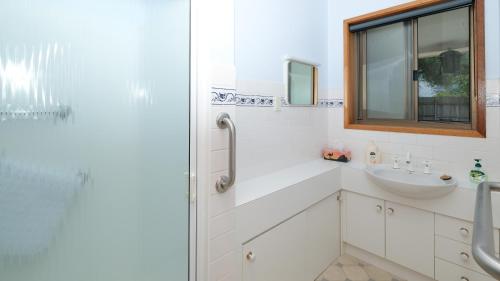 a white bathroom with a sink and a shower at Marlo at the Beach in Marlo