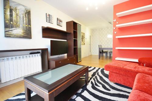 a living room with a red couch and a tv at GALIHOST - Piso con parking en pleno centro de Cambados in Cambados