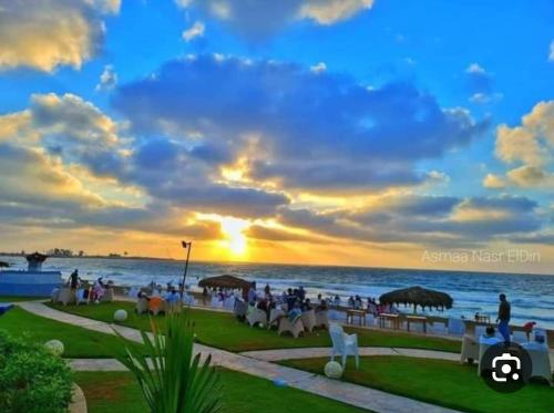 um grupo de pessoas sentadas na praia ao pôr do sol em LARA Maamoura beach Alexandria em Alexandria