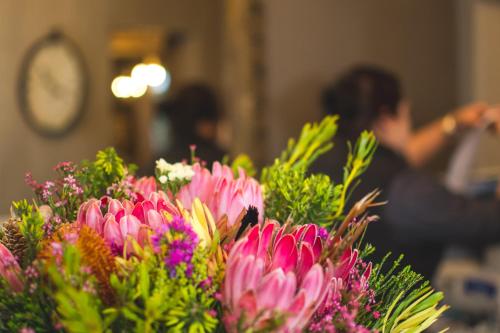 a bunch of pink flowers with a woman in the background at The Post House Hotel - no children under the age of 16yrs in Greyton