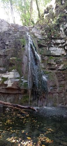 a waterfall on the side of a rock wall next to a pond at AL CORNIOLO in Zerba