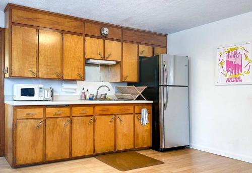 a kitchen with wooden cabinets and a stainless steel refrigerator at Whimsical apartment near downtown Winooski in Winooski