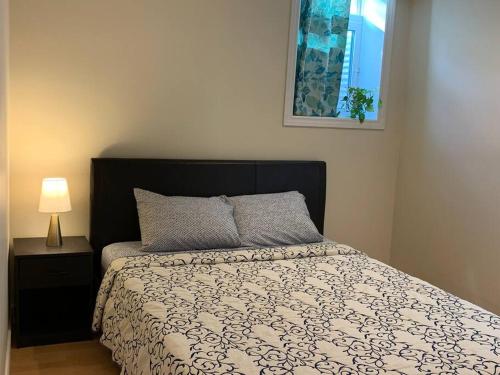 a bedroom with a bed and a lamp and a window at Finished 2 BR Apartment in an Upscale Area of Ajax in Ajax