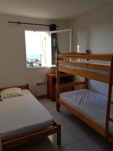 une chambre avec deux lits superposés et une fenêtre dans l'établissement Nice house with pool - near the beach, à Saint Pierre La Mer