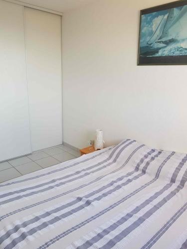 - un lit avec une couverture rayée bleue et blanche dans l'établissement Nice house with pool - near the beach, à Saint Pierre La Mer