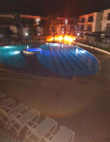 a swimming pool at night with white chairs around it at Apartasol Ciudadela Santafe in Santa Fe de Antioquia