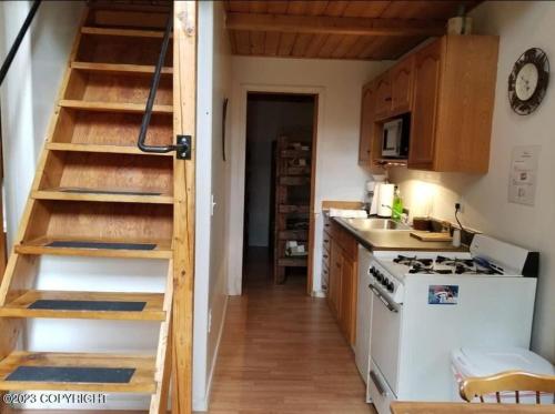 una pequeña cocina con fogones y una escalera en Bear Necessities Alaska en Seward