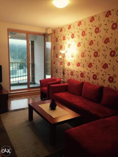 uma sala de estar com um sofá vermelho e uma mesa em Apartman Babin Do Bjelasnica em Sarajevo