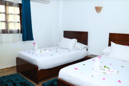 Jasmine Nile apartments في الأقصر: سريرين في غرفة في الفندق وعليها زهور