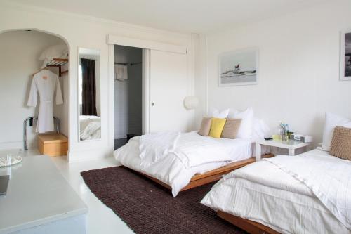 a white bedroom with two beds and a mirror at Sole East Resort in Montauk
