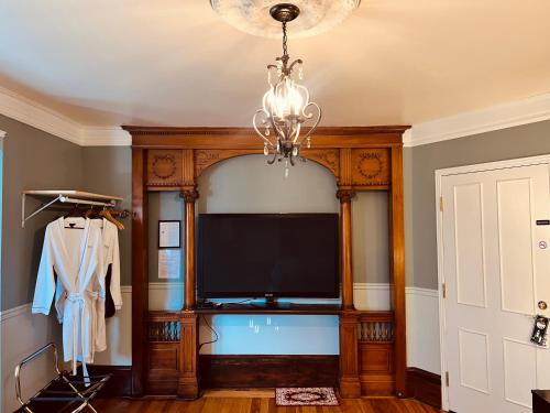 a living room with a television and a chandelier at Le Chateau du Lac in Magog-Orford