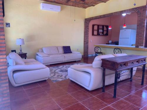 a living room with couches and a table and a kitchen at Casa Jardin in Lo de Marcos