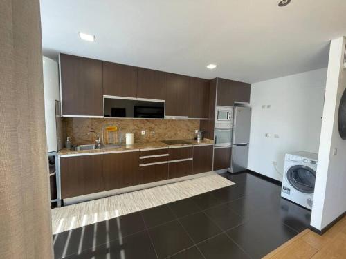 a kitchen with brown cabinets and a washer and dryer at Ap.Maria Bonita in Carreira