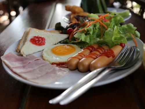 Een bord met ontbijtproducten zoals eieren, vlees en salade. bij TonSilp Art Home in Nong Nam Daeng