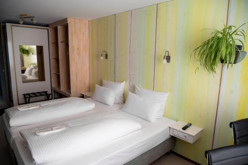 a bedroom with a white bed with a plant on the wall at Abalon Hotel ideal in Stuttgart