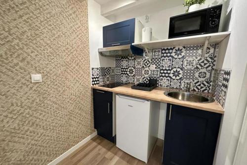 une petite cuisine avec un évier et un micro-ondes dans l'établissement Appartement douillet avec terrasse, à Talence