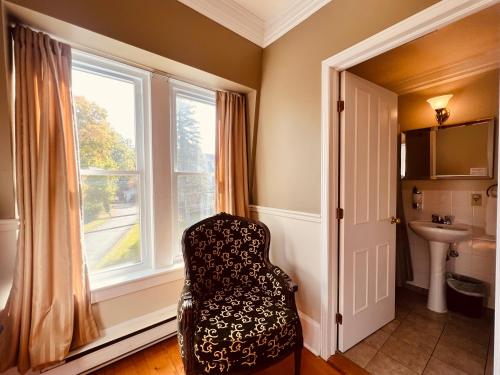 a bathroom with a chair in front of a window at Le Chateau du Lac in Magog-Orford