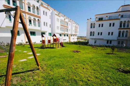 a yard with a playground in front of a building at appartement de vacances achakar avec plage&piscine in Tangier