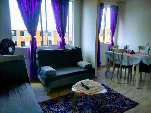 a living room with purple curtains and a couch and a table at Acogedor Apartamento Arboleda del Campestre in Ibagué